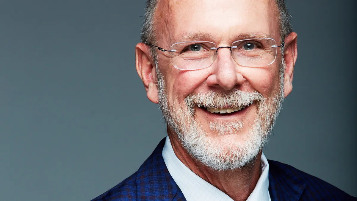 A man in a suit smiles for a photograph