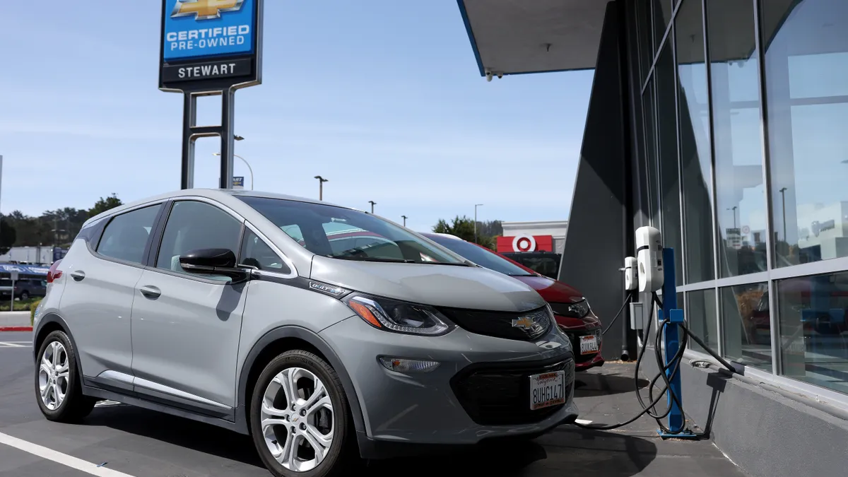 A light gray Chevrolet Bolt EV parked outside at a charging station at a Chevrolet dealer in Colma, California.