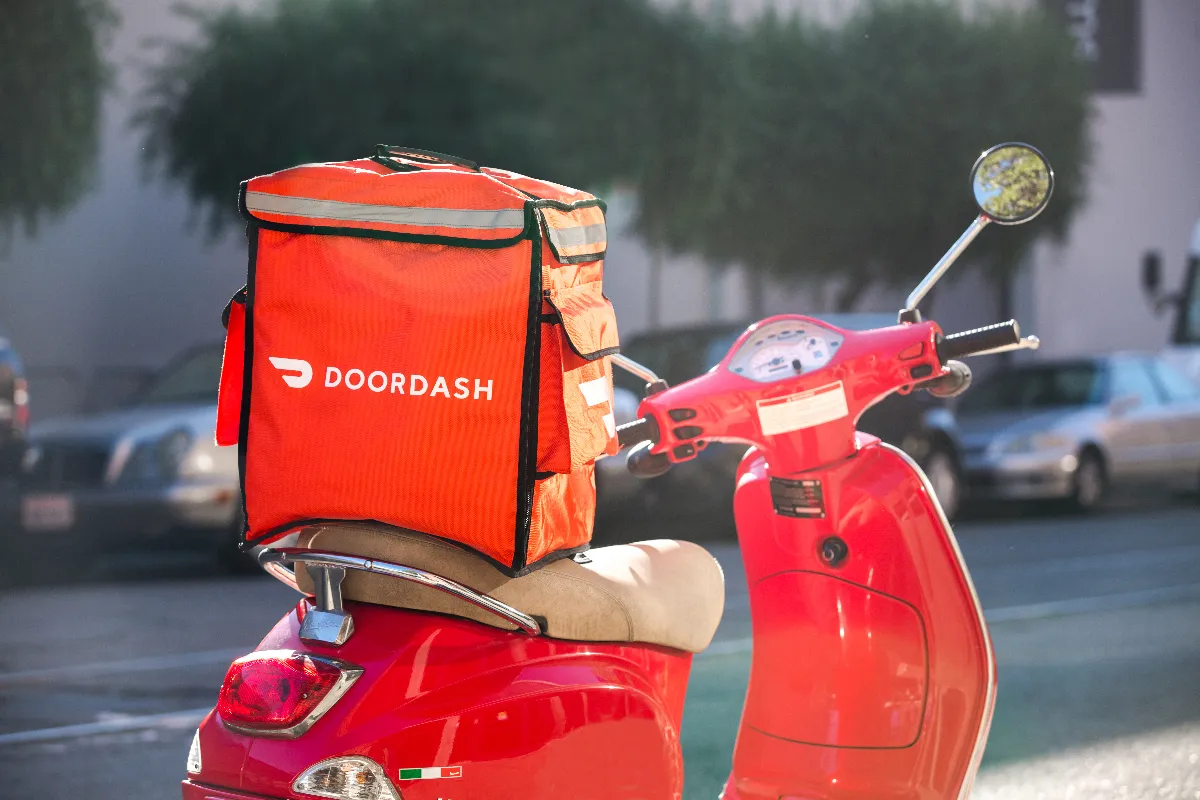 An image of a red scooter with a DoorDash bag on it.