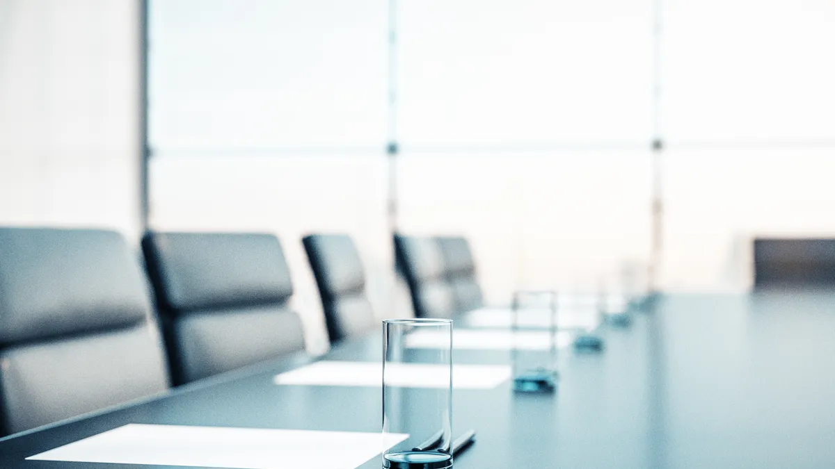 Close up of conference room with glasses of water on the table with papers, armchairs and a large window.