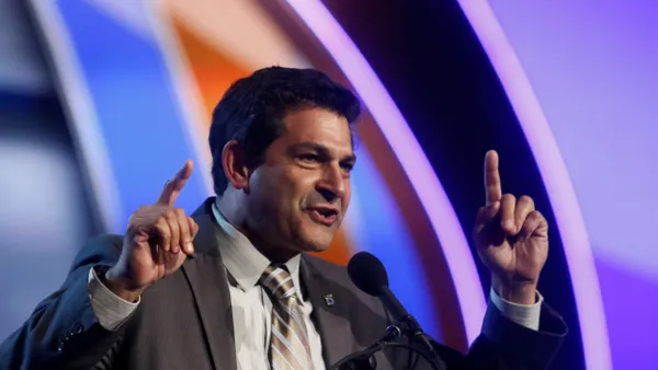 The secretary-treasurer of the Teamsters Local 2010 union raises his arms as he speaks on a stage.