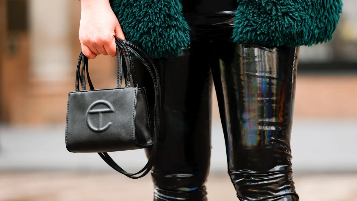 A detailed picture of a person holding a small Telfar handbag.