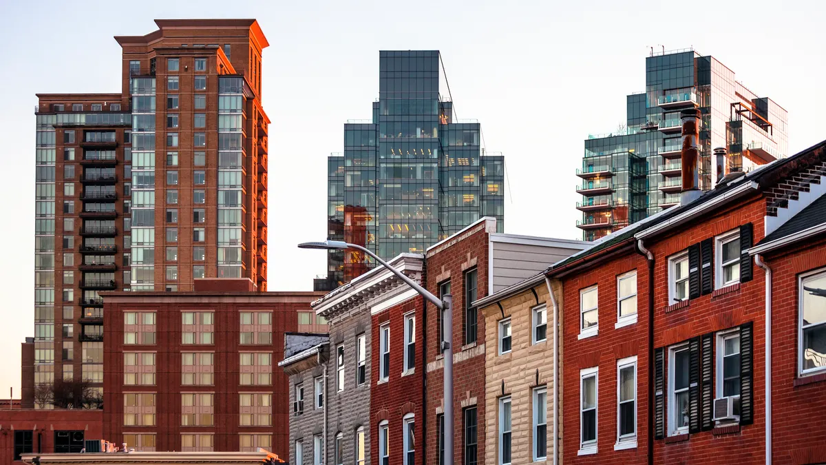 A row of brick homes with tall office buildings in the background.