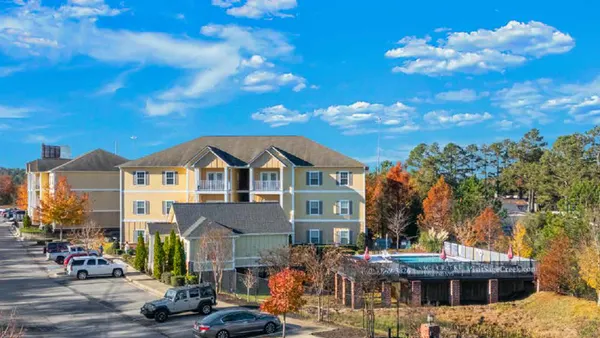 Three-story garden style apartments surrounded by pool, parking lot and trees