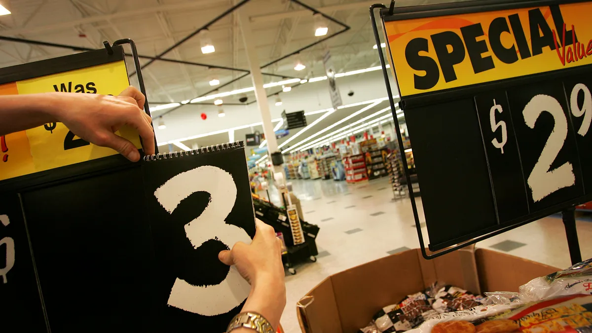 A worker's hands are shown changing the price on a box of produce.