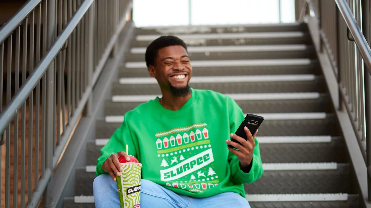 A photo of a person in a 7-Eleven sweater sitting on stairs.