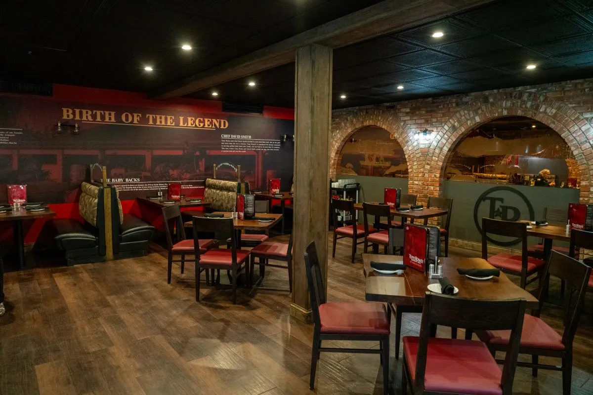 An image of a dining room with red booths and four-seater tables with red chairs.