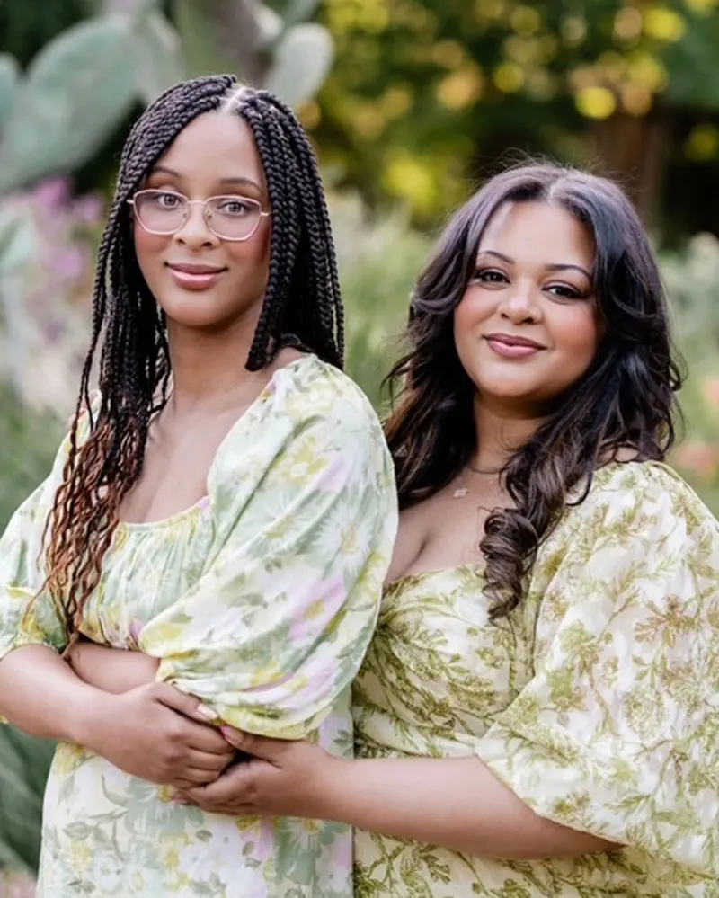 Two people are standing outside and standing close side to side.