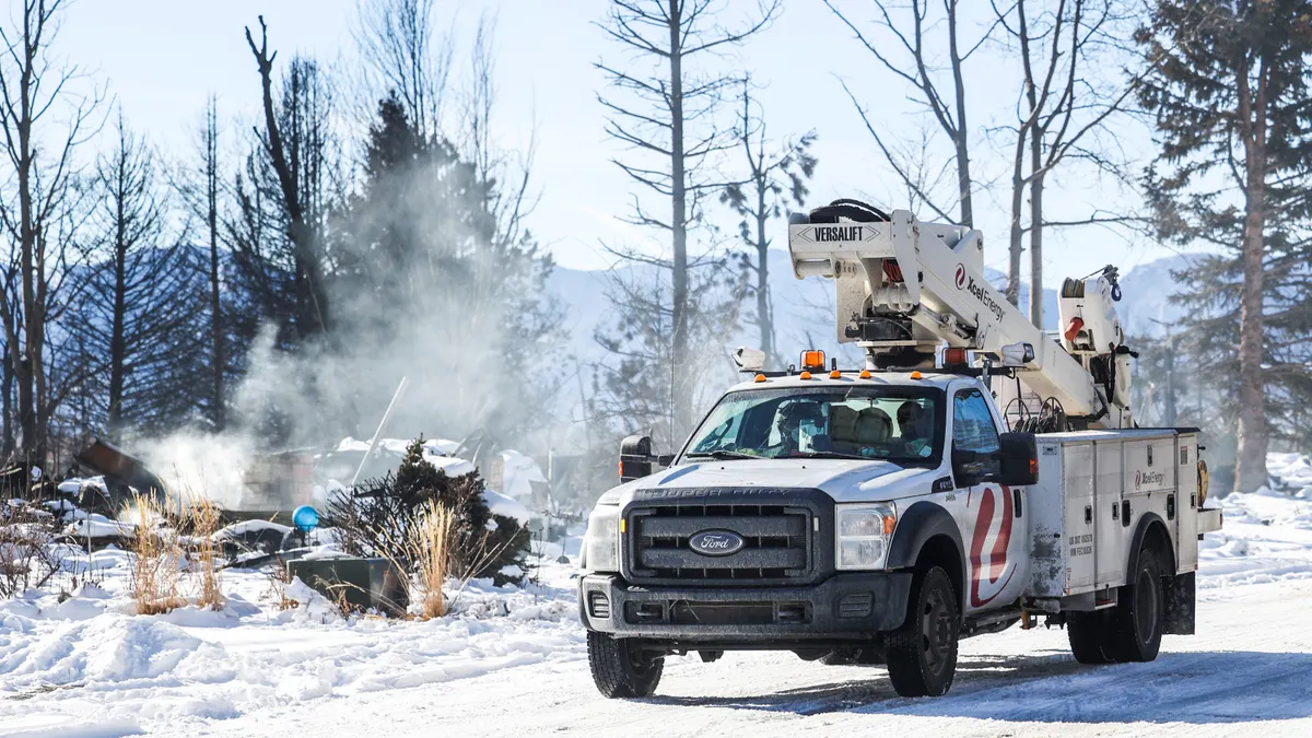 An electric utility truck drives down a street after a wildfire.