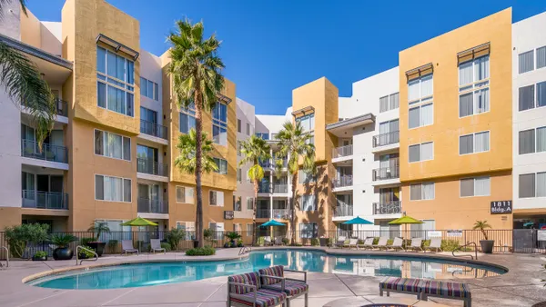 Yellow apartment building with trees and pool inthe foreground
