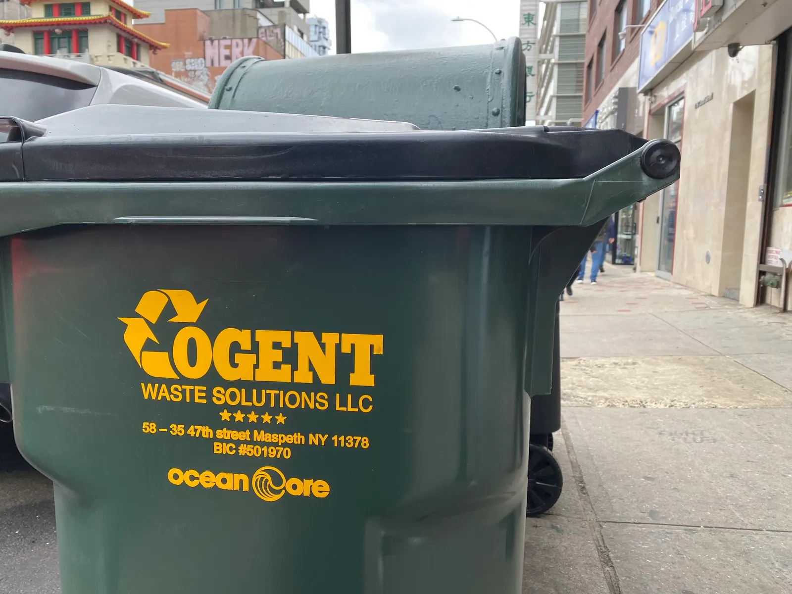 A trash cart with the Cogent Waste Solutions logo in New York