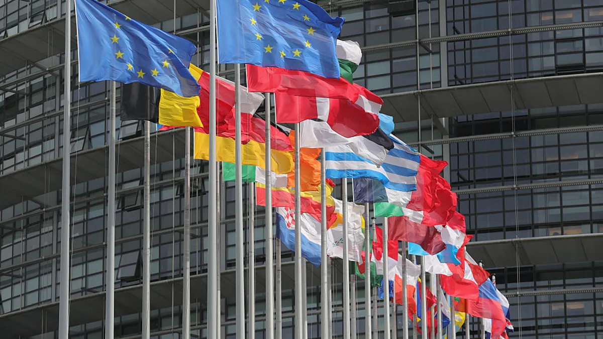 a set of flags multicolored flags representing the European Union and associated nations wave outside of its headquarters.