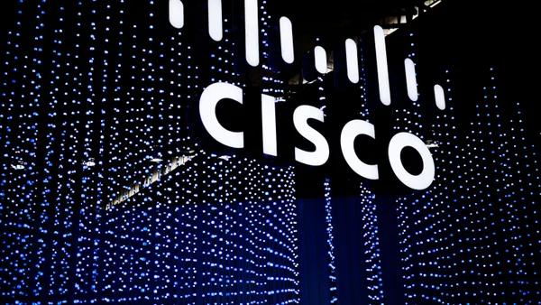 The Cisco logo is seen suspended in the air in front of an array of blue lights