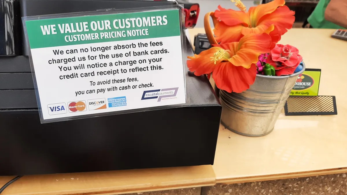 Notice on counter next to cashier tells customers about credit card surcharge