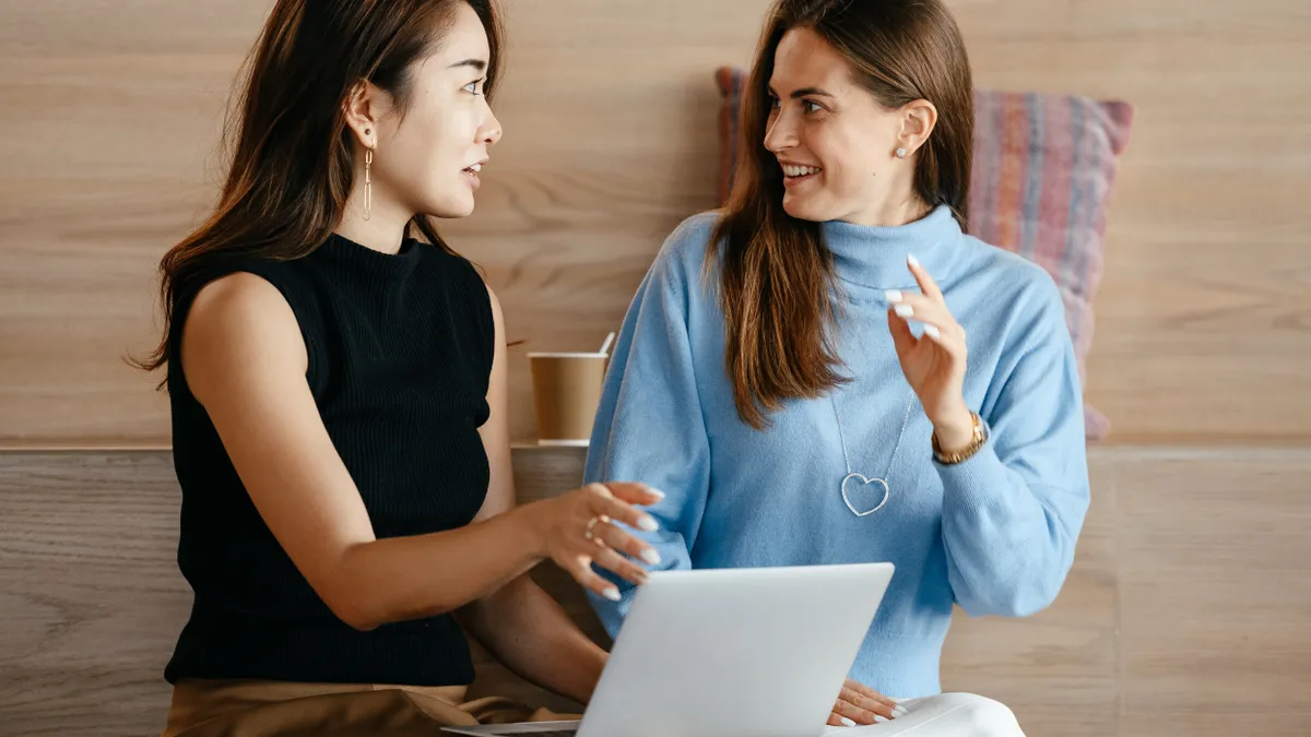 Two feminine-presenting people are talking in an office