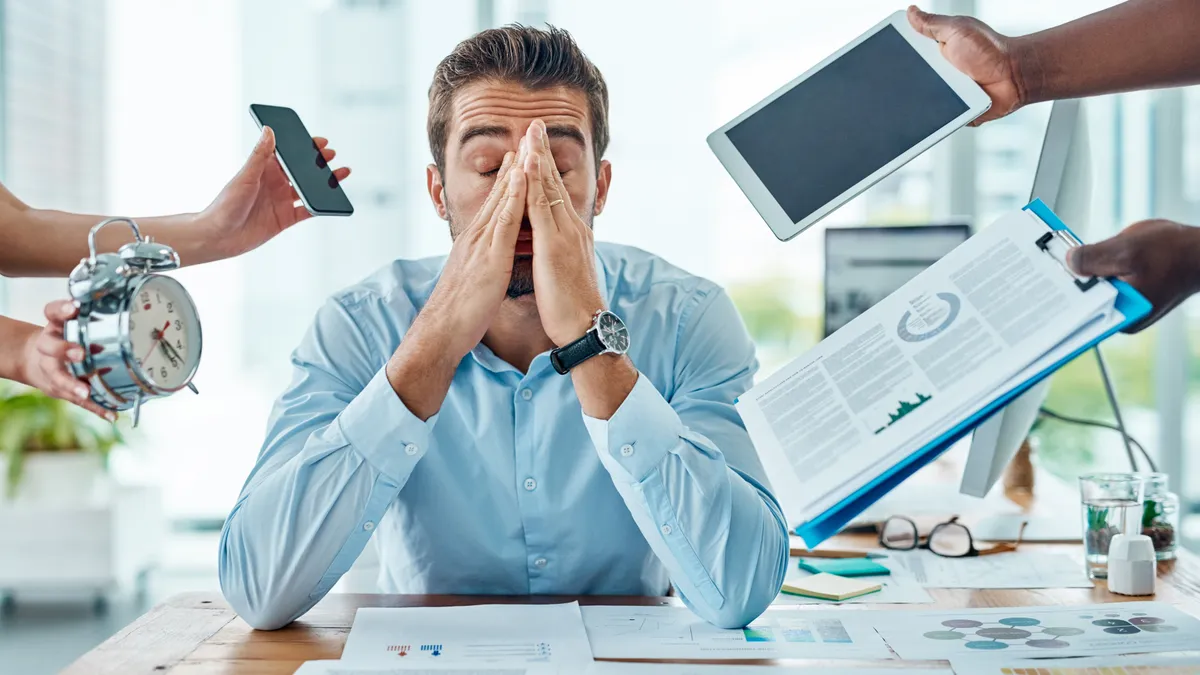 A lawyer looking stressed out as coworkers put digital devices and paperwork in front of them