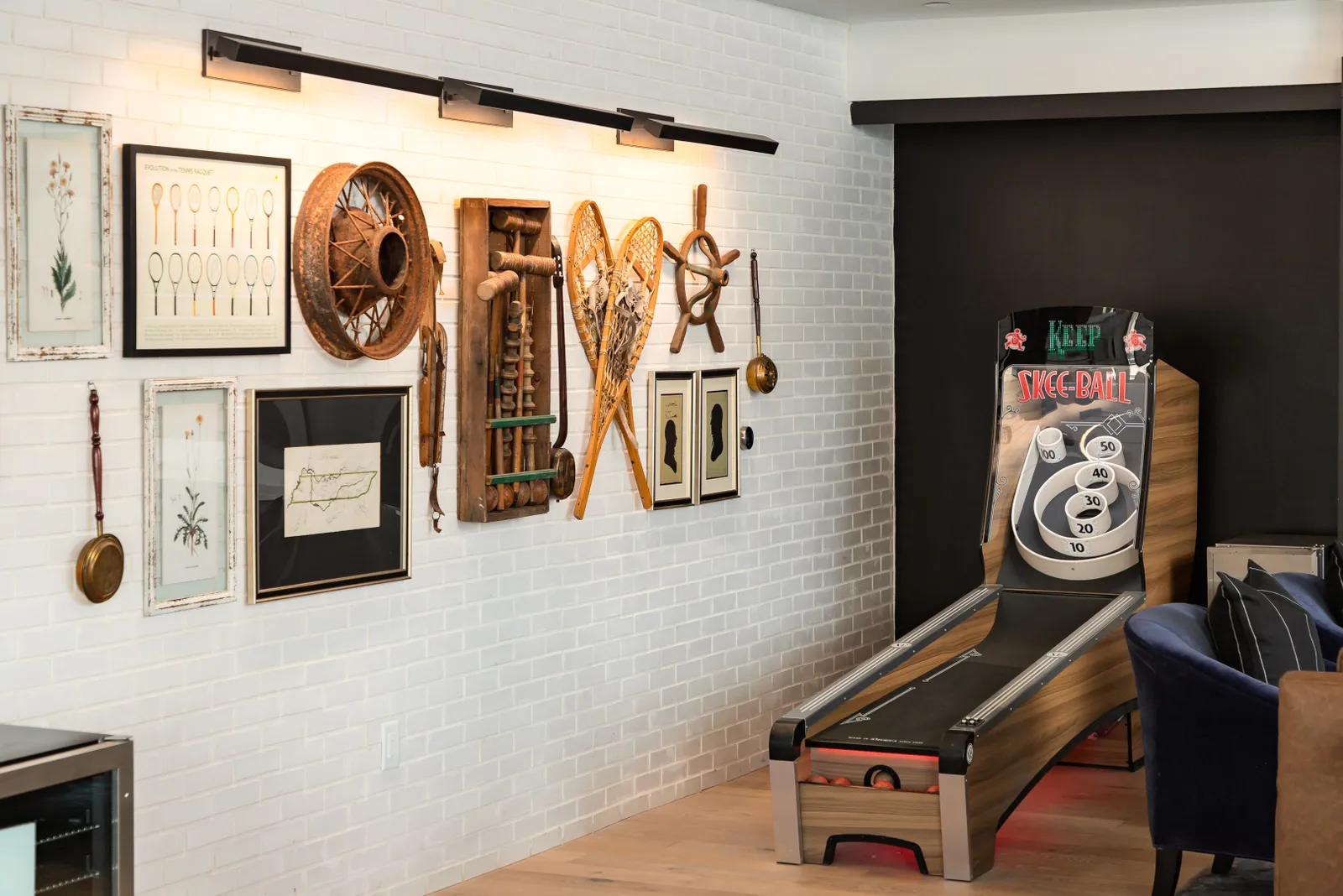 A room with a Skee Ball machine and a variety of decorations on a brick wall.