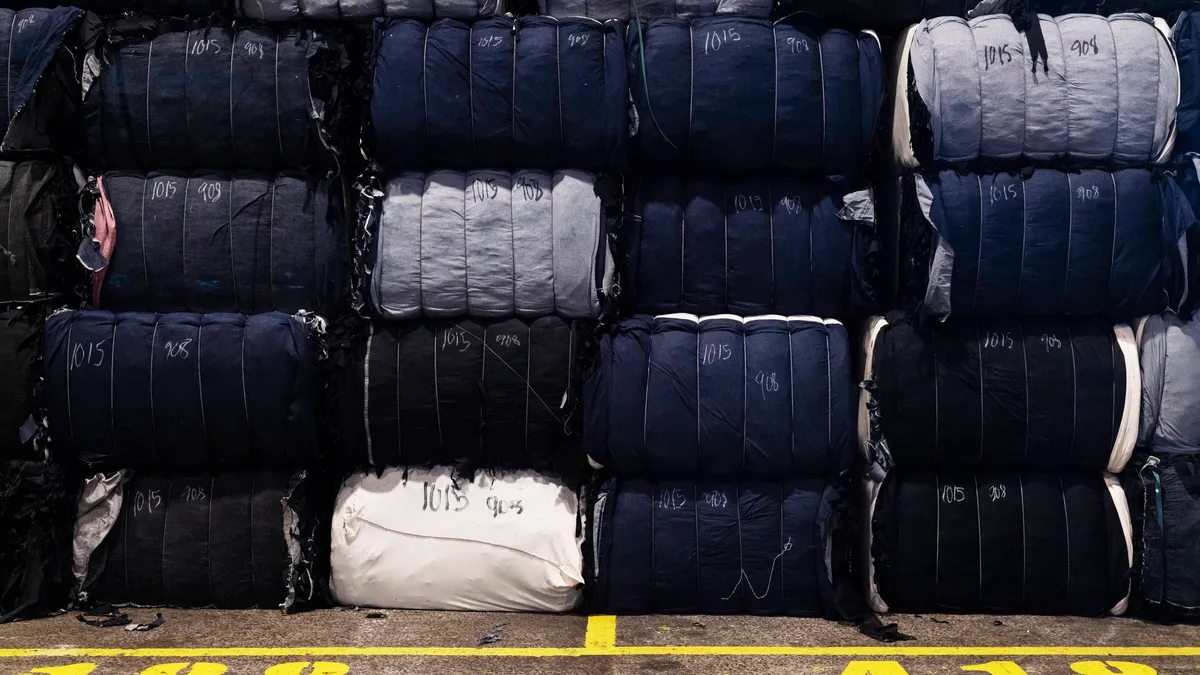 Textile waste is shown stacked on top of each other in a factory setting.