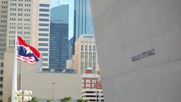 A city hall building looms over the city's downtown, with flags waving on the left.