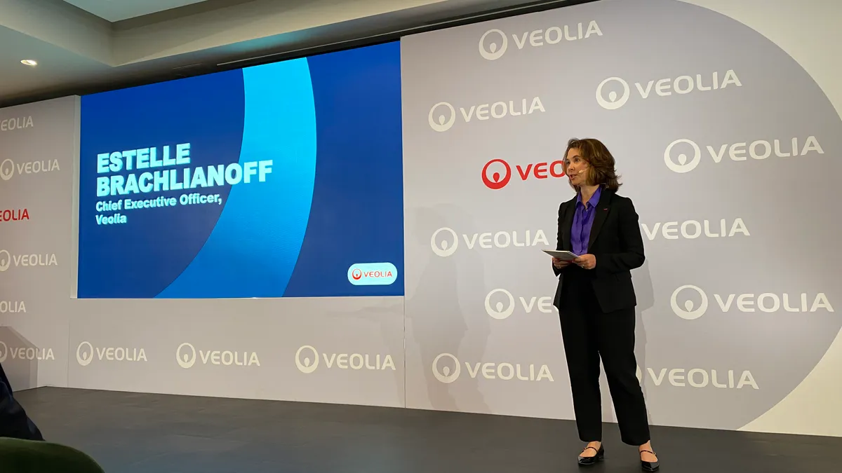 A woman stands on a stage in front of a projected screen with Veolia branding.