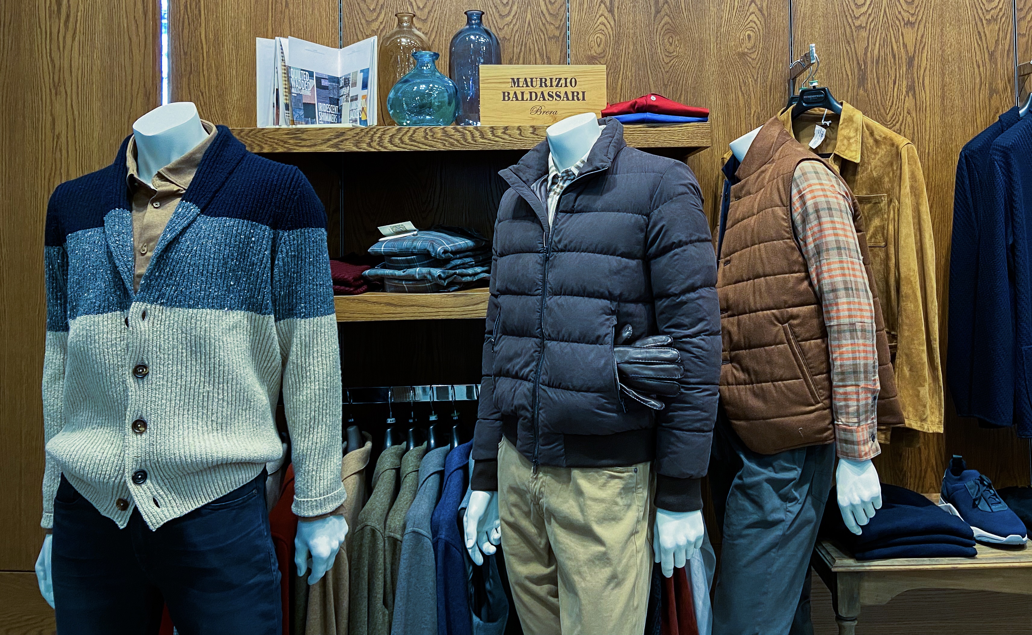 A store display of casual clothing including sweaters, shirts, jackets, pants and sneakers.