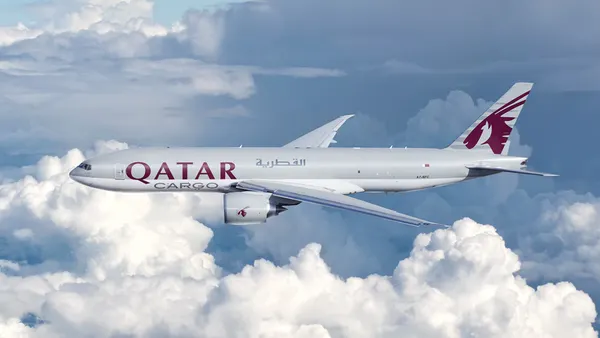 A "Qatar Cargo" branded aircraft flights through a sky with clouds