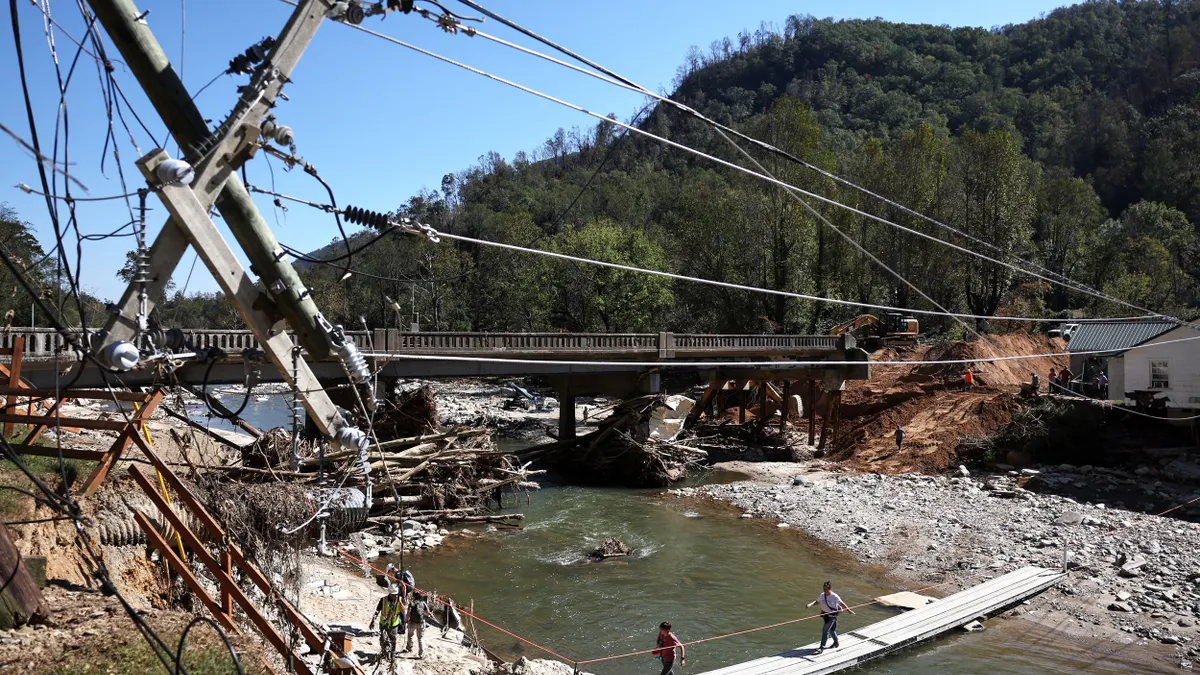 People walk across a makeshift bridge as a damaged bridge is repaired.