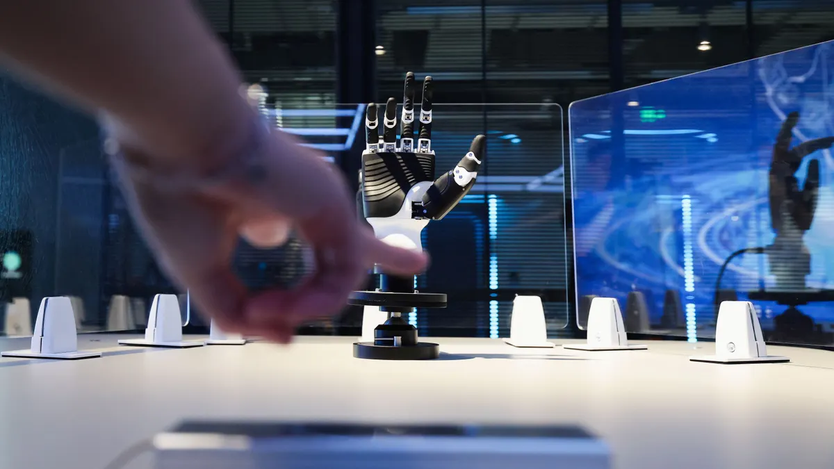 A human hand points at a black and white robot hand displayed at an embodied robot store in China.