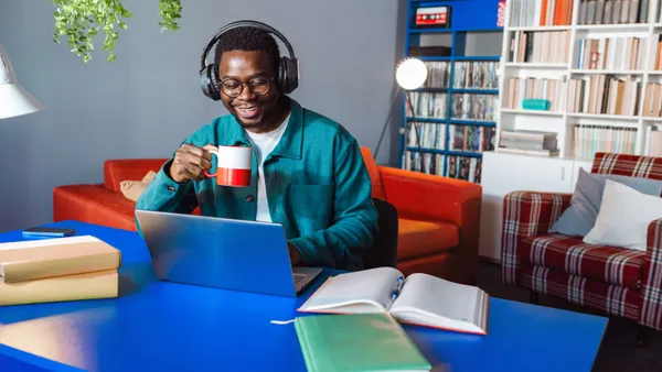 Male working on laptop while sipping coffee and smiling