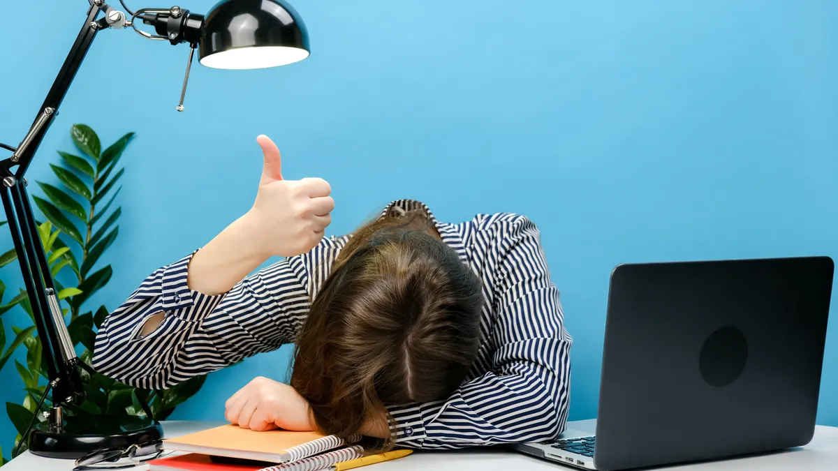 Exhausted employee with her head down in her desk