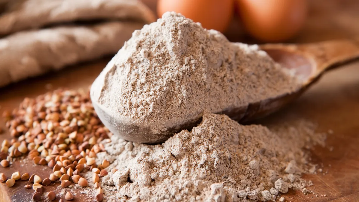 Buckwheat flour overflowing on wooden spoon