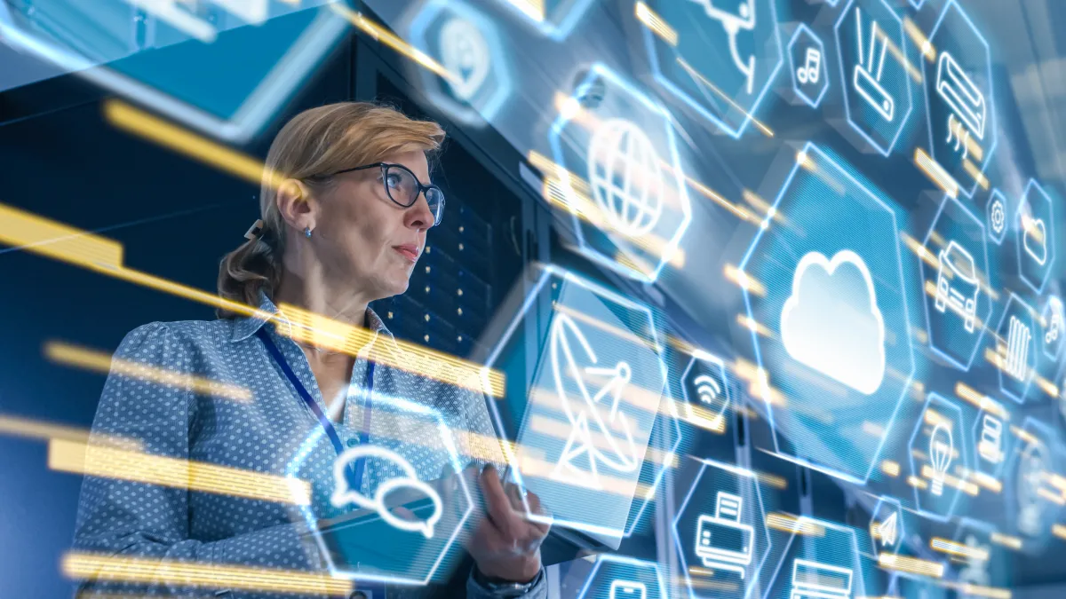 Female IT Server Specialist Standing in Data Center. View from Rack Server Cabinet with Cloud Server User Interface Icons and Visualization in the Foreground.