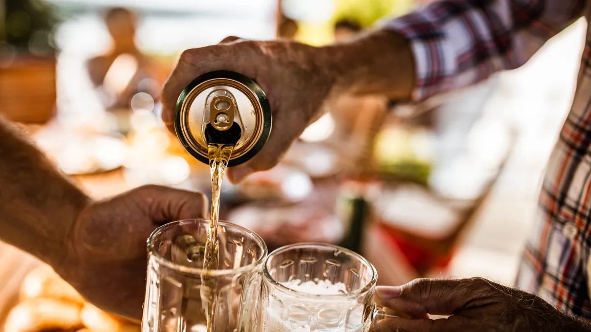 Close up of a person pouring beer from a can into beer glasses.