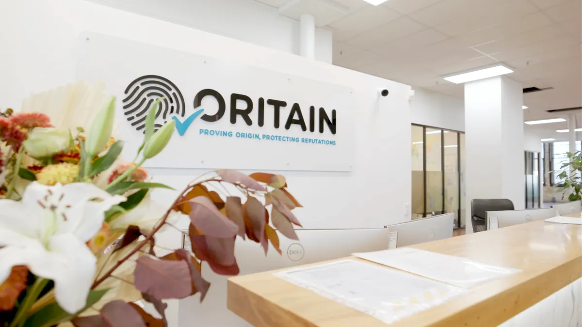 The front desk at Oritain shows a cream colored room with flowers and an Oritain logo.