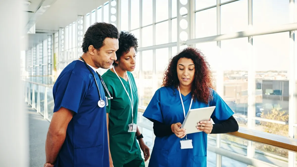 Nurses discussing paperwork in the hallway of a hospital