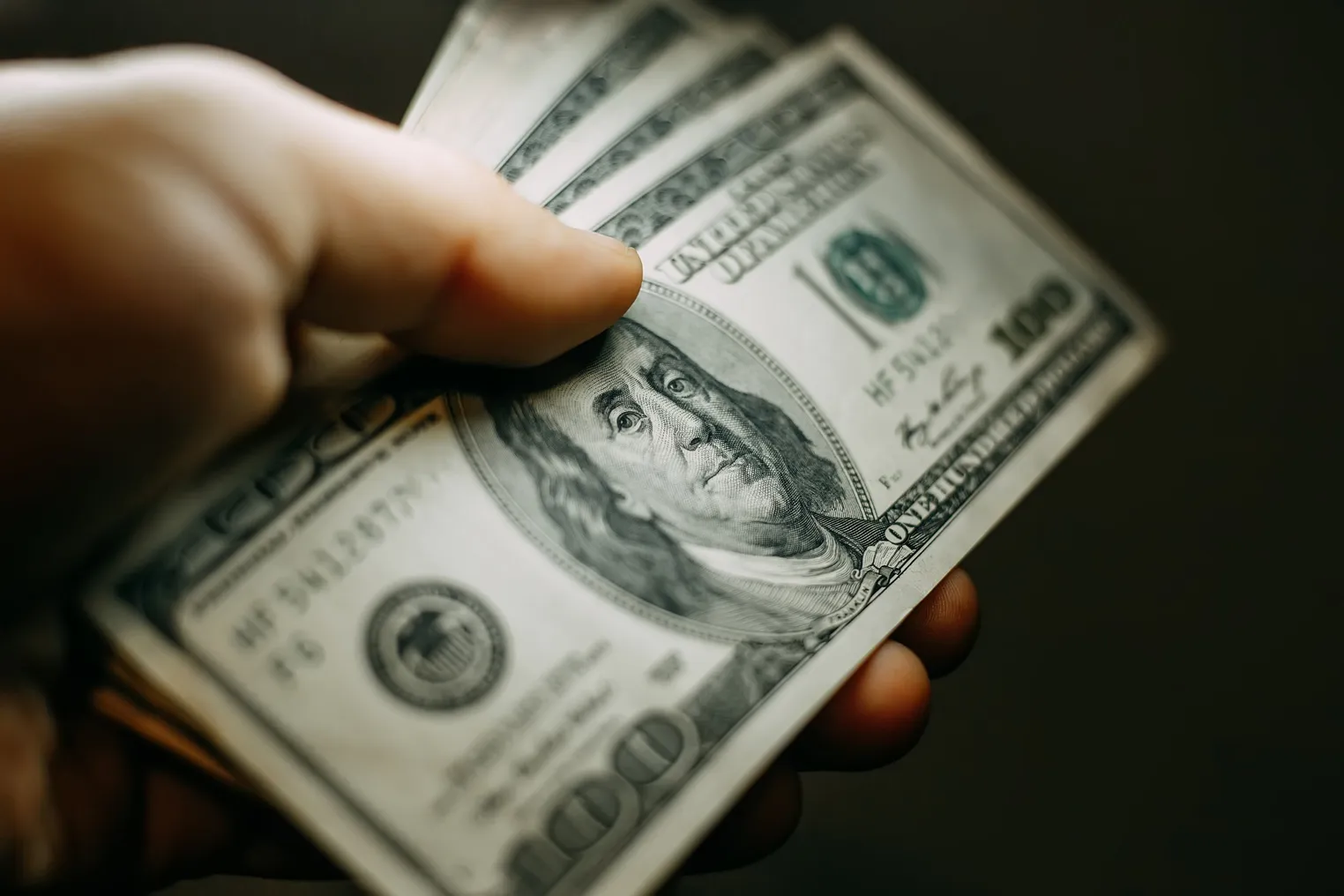 Hand with a stack of hundred US dollars bills, close up