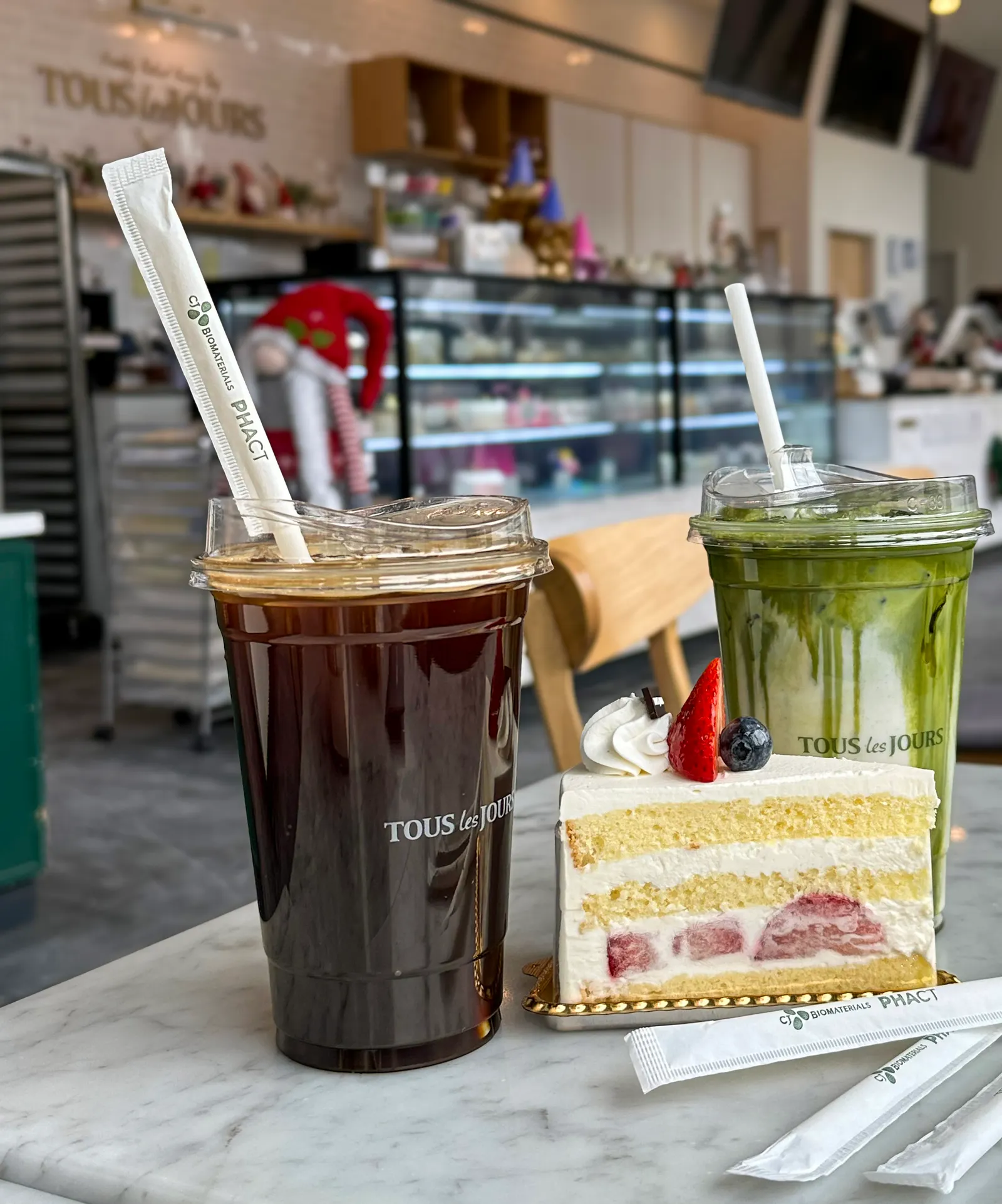 Two plastic cups with CJ Biomaterials straws, with a piece of cake in between, at a Tous les Jours cafe