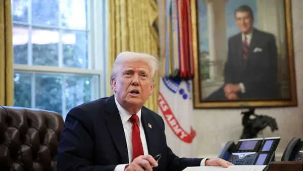 Donald Trump speaks while signing an executive order at his desk.
