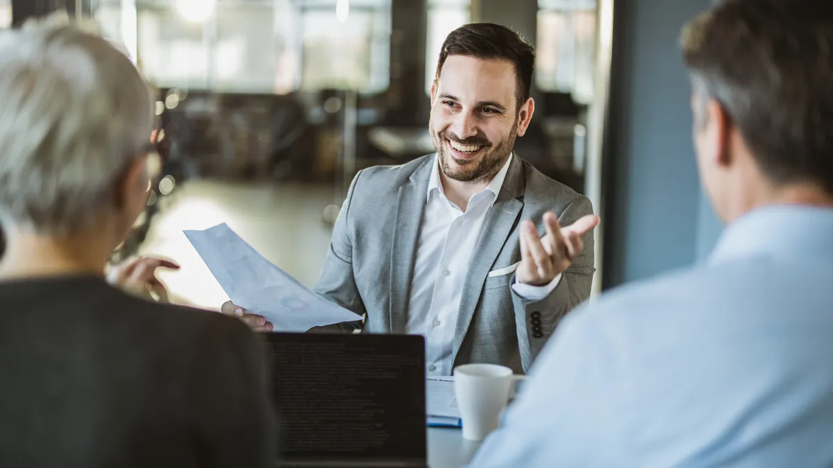 Happy businessman talking to his colleagues on a meeting in the office