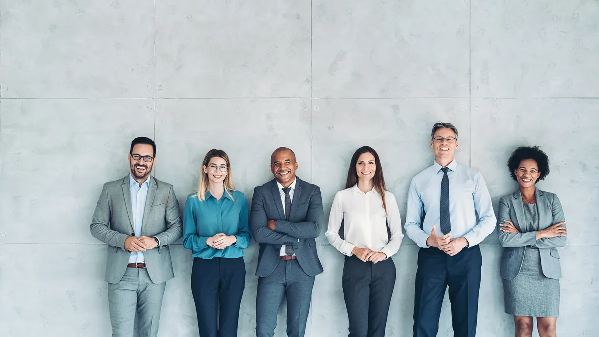 A photo of a group of diverse people standing outside against a wall