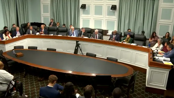 Men and woman sitting along a large desk.