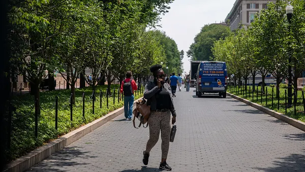 A person walks on a pathway at Columbia University talking on the phone.