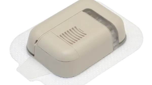 A rectangular, plastic device sits on an adhesive patch.