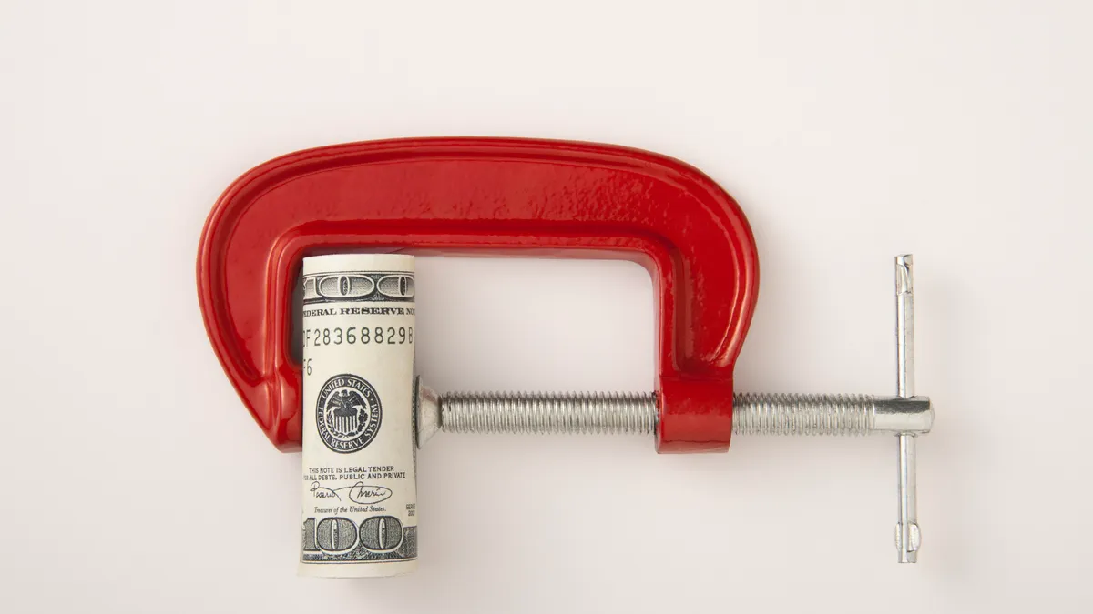Money roll clamped in a red clamp on a white background