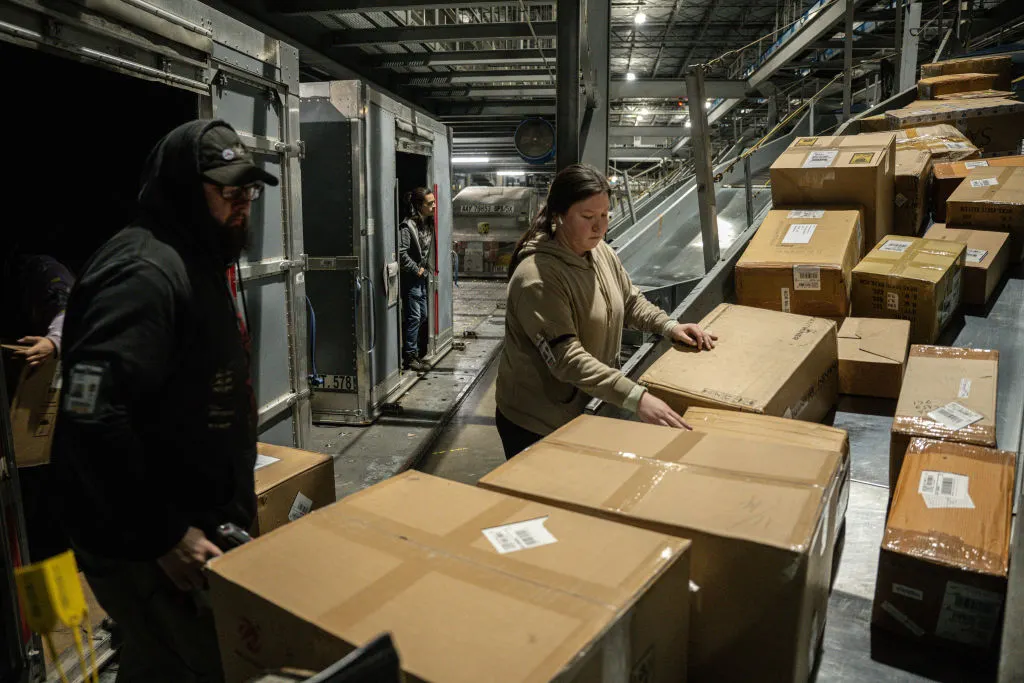 UPS employees load boxes from a posi-sorter chute into an air container at UPS Worldport on January 3, 2022 in Louisville, Kentucky.
