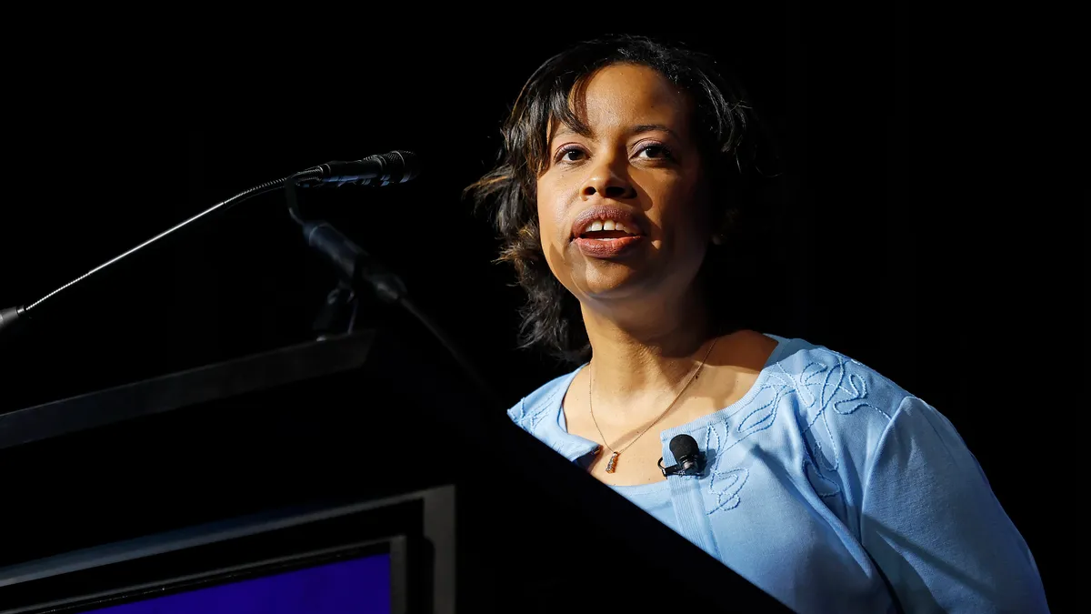 Chiquita Brooks-LaSure speaks behind a podium in front of a black background.