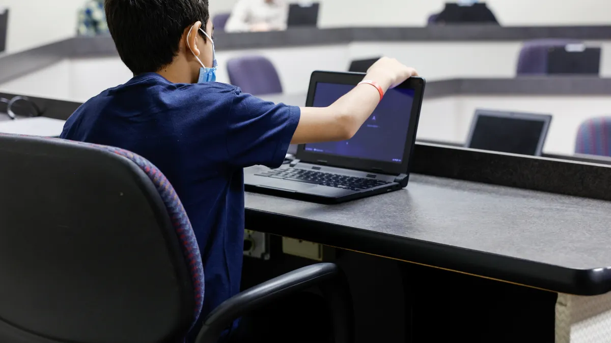 A young boy looks at a laptop in a computer classroom.