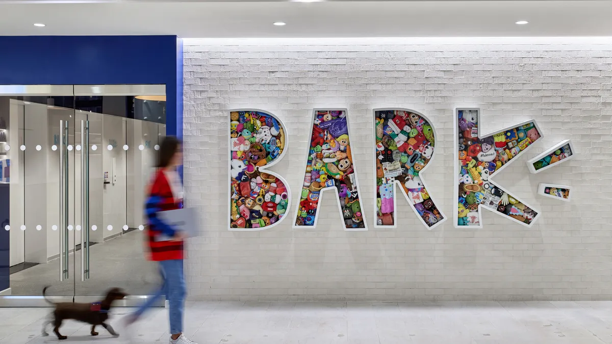 A person walking by a Bark sign