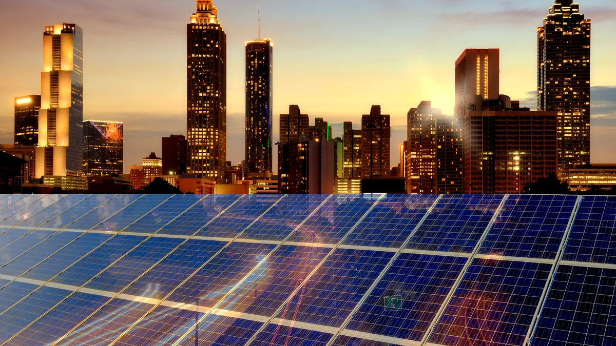 A commercial building bears rooftop solar panels facing the twilit skyline of Atlanta, Georgia