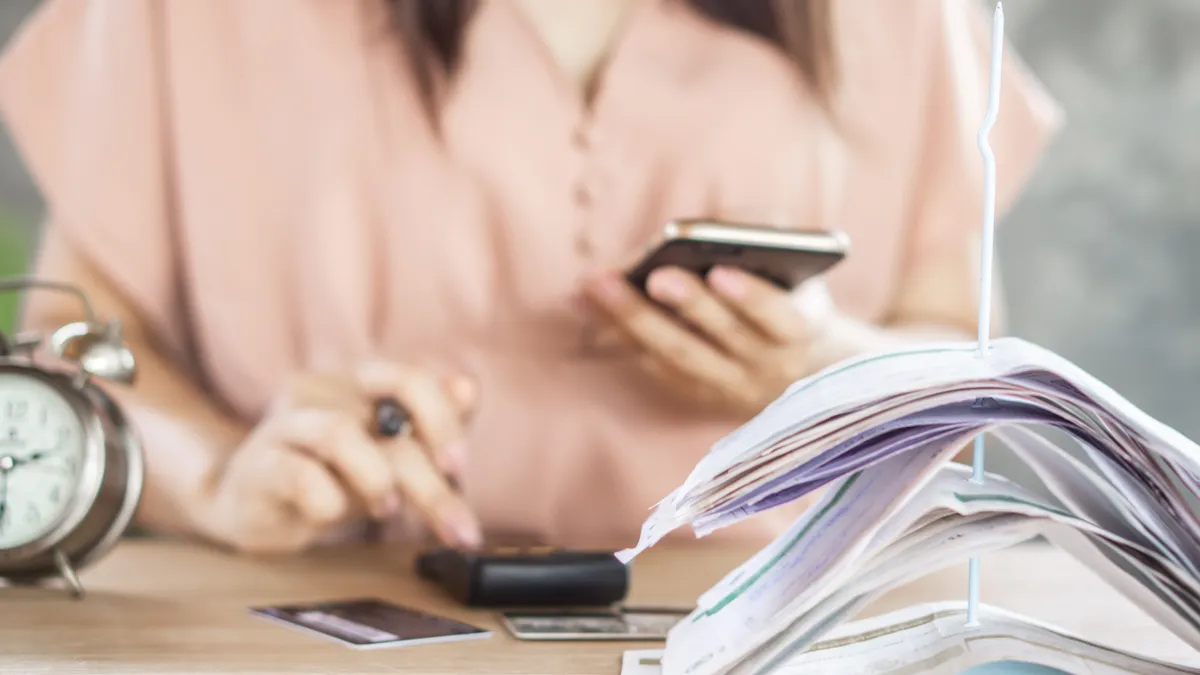 woman hand counting expenses with smart phone and credit cards